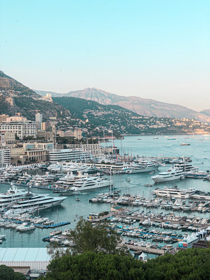Aerial view of luxury yachts in Monacos picturesque harbor with mountains in the background.